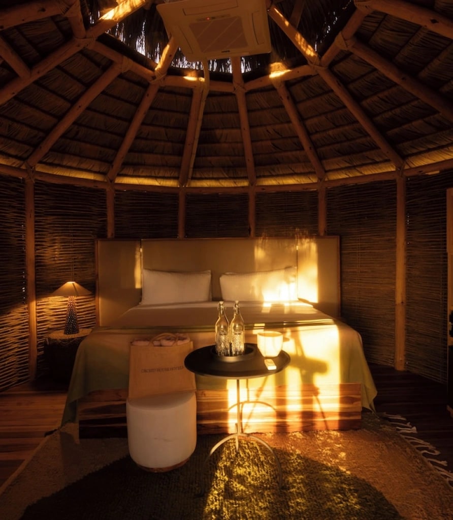 Inside the round bungalow, with a conical timber roof and a lit bed