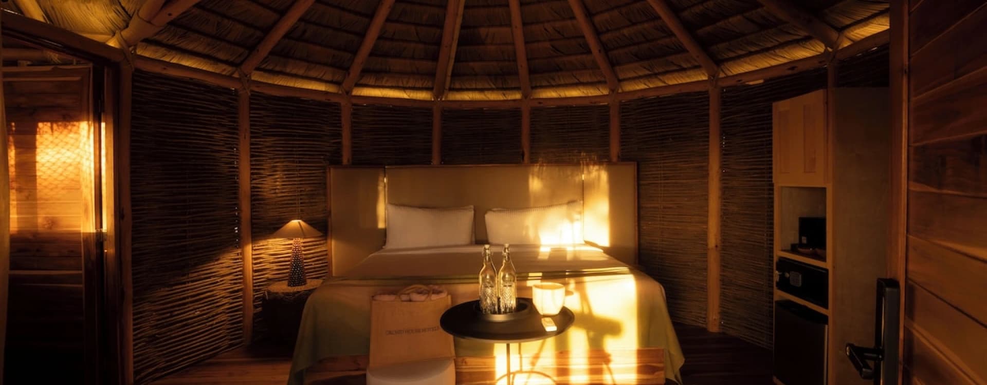 Inside the round bungalow, with a conical timber roof and a lit bed