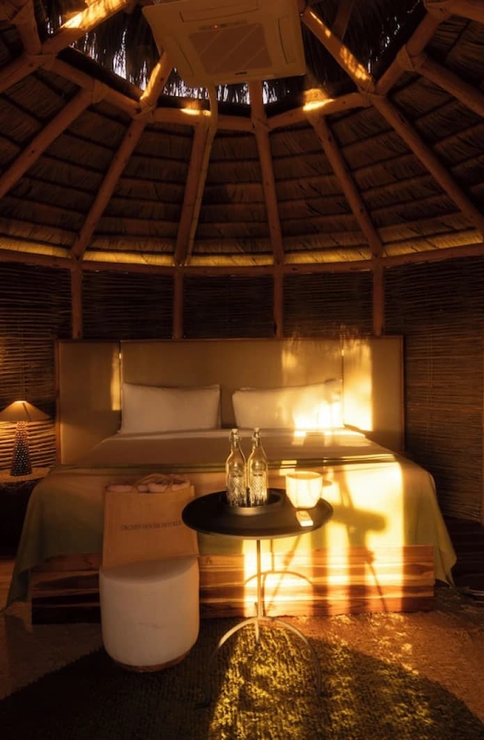 Inside the round bungalow, with a conical timber roof and a lit bed
