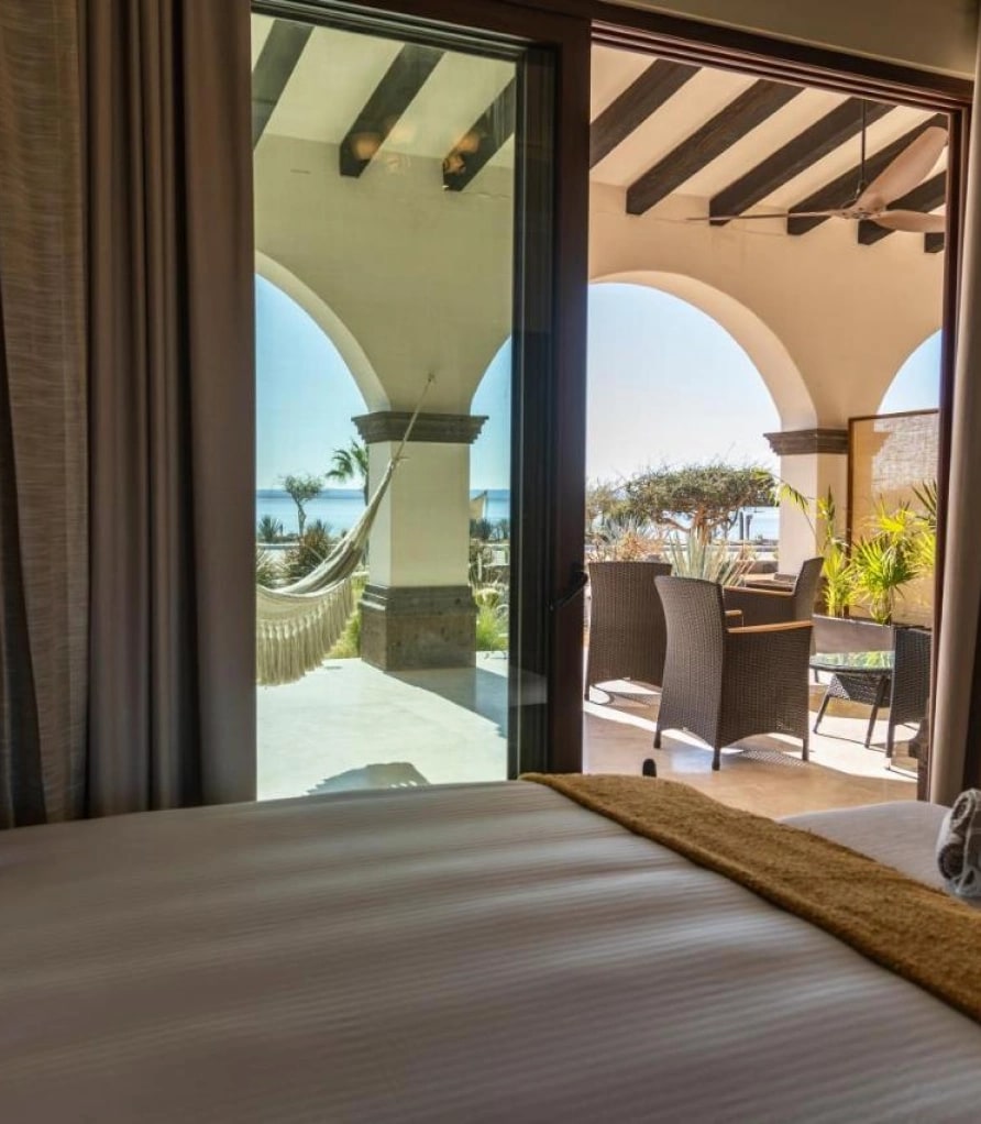 Bedroom with a bed facing the open arches of the patio and the hammock