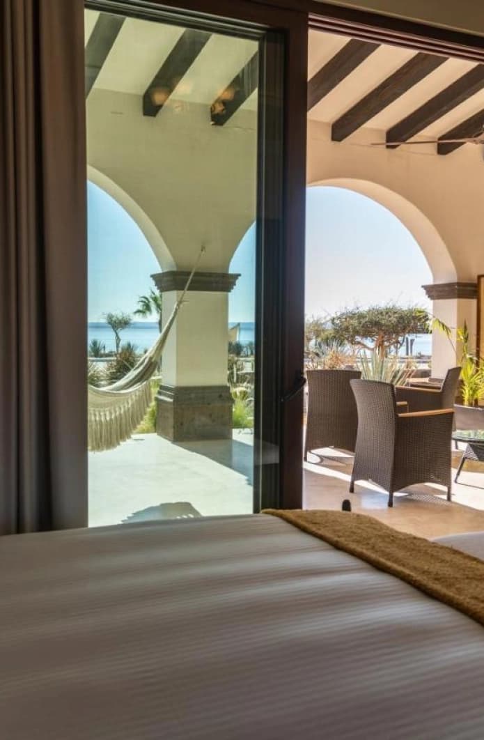 Recámara con cama king frente a los arcos abiertos del patio y la hamaca