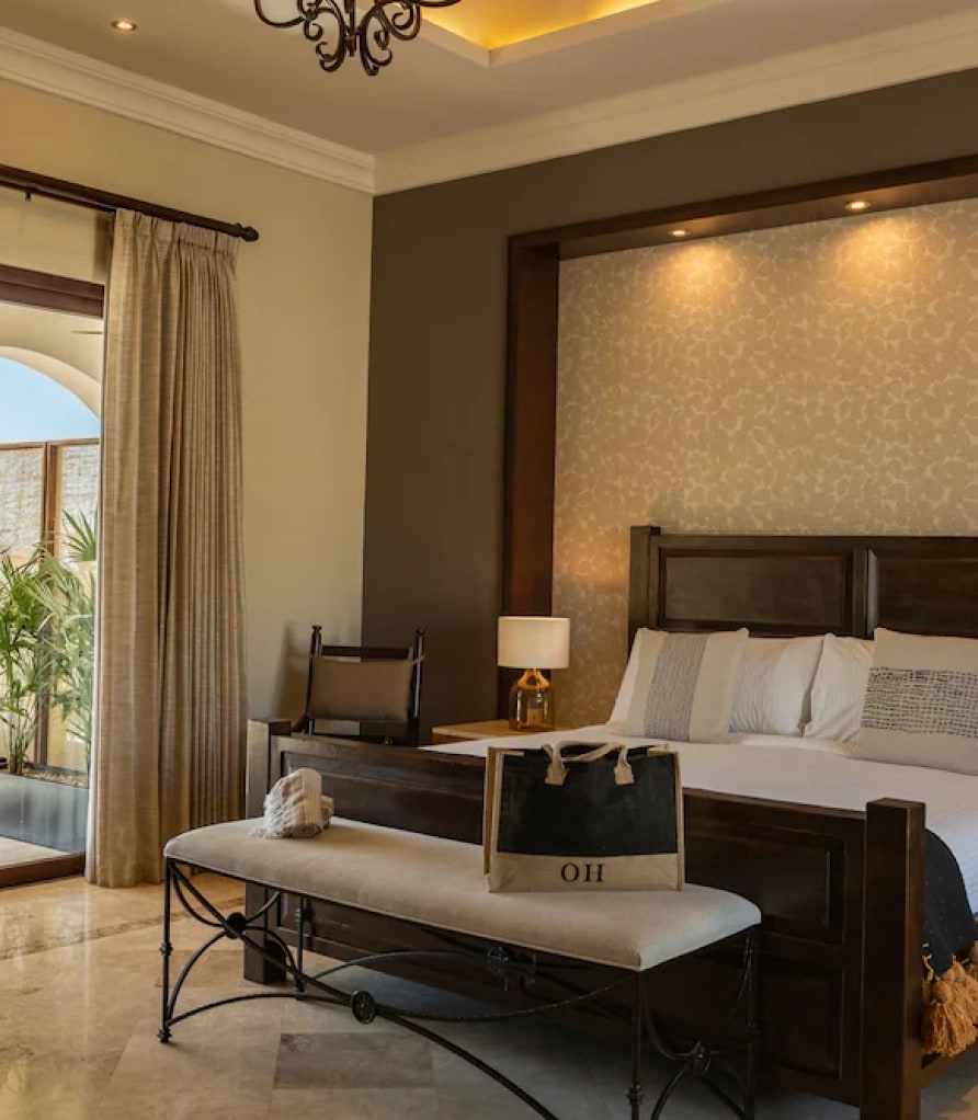 Dark timber king bed with a bench at the foot and a lit headboard panel