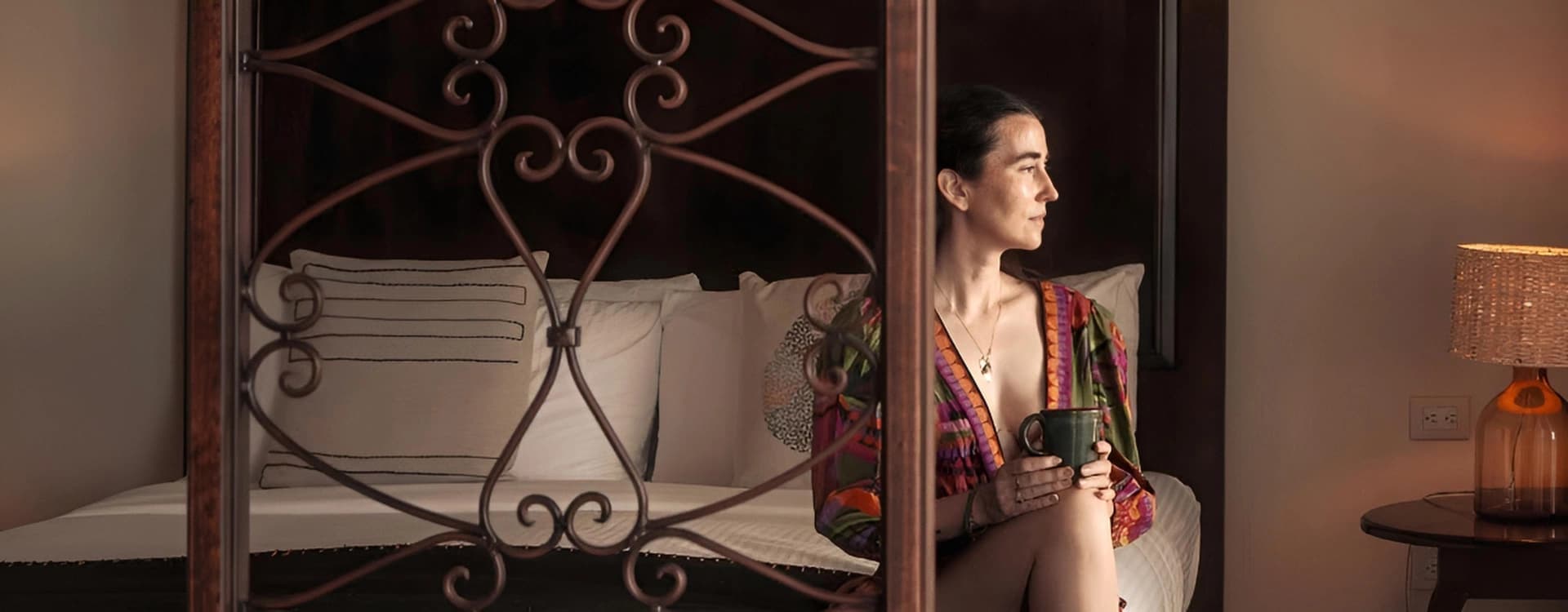 Cama de dosel de herrería detrás de un biombo de forja
