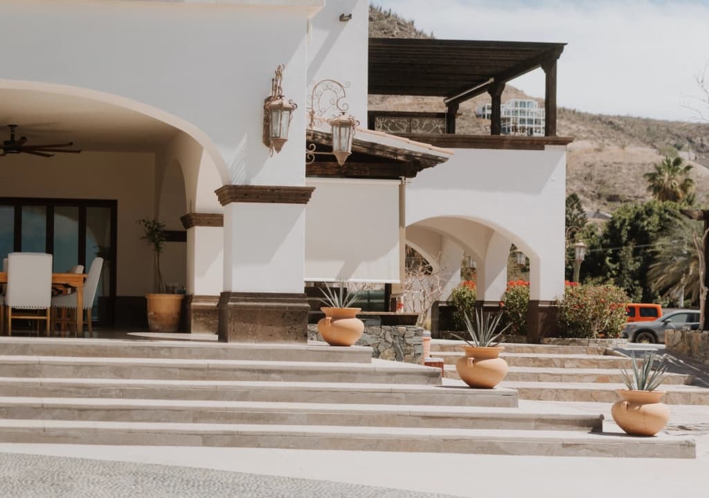 Escalinata de acceso a la casa, flanqueada por macetas de barro con agaves