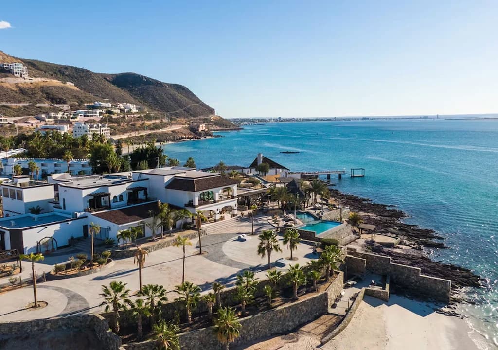 Vista aérea de la casa de Baja sobre la punta rocosa, entre palmeras y frente al Mar de Cortés