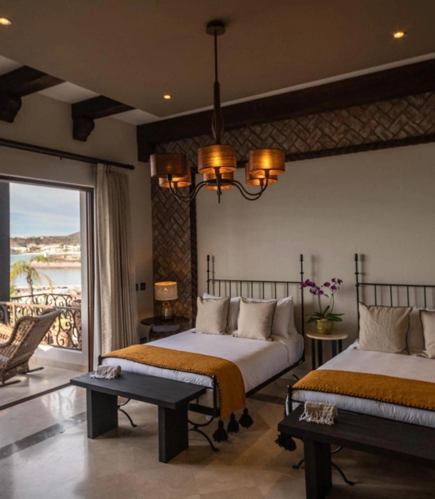 Two wrought-iron beds with a bench at the foot and a shaded chandelier