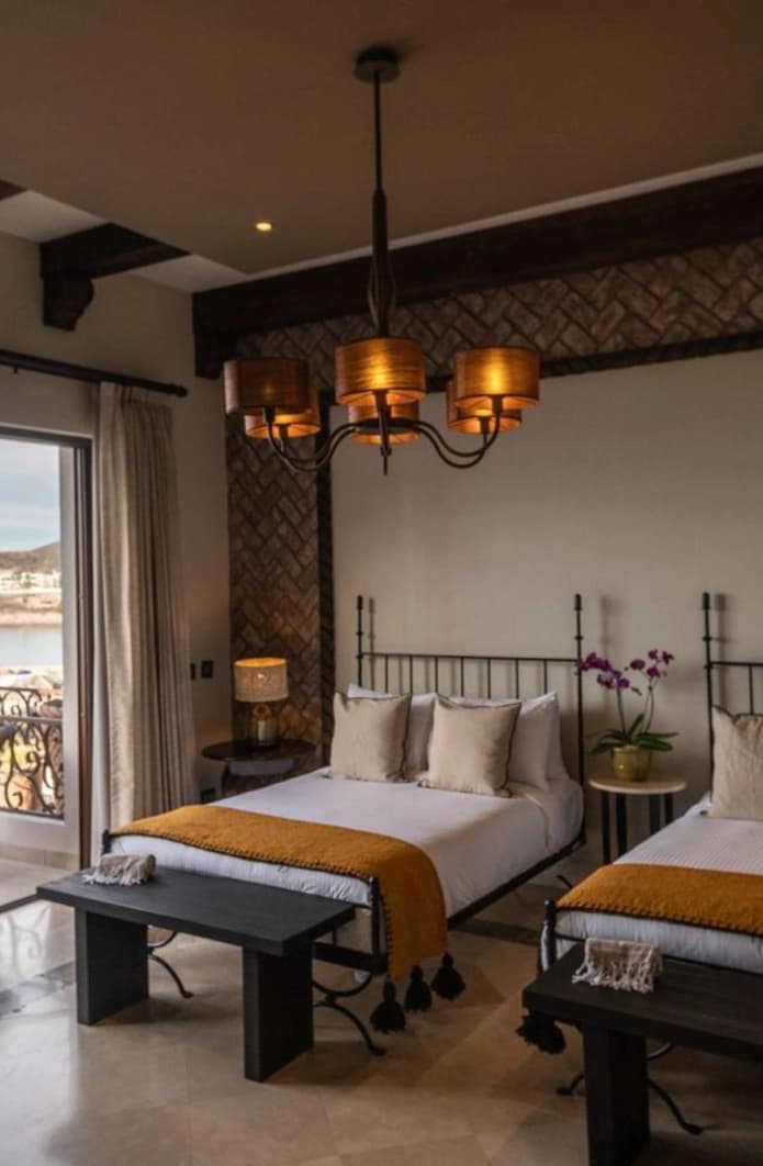 Two wrought-iron beds with a bench at the foot and a shaded chandelier