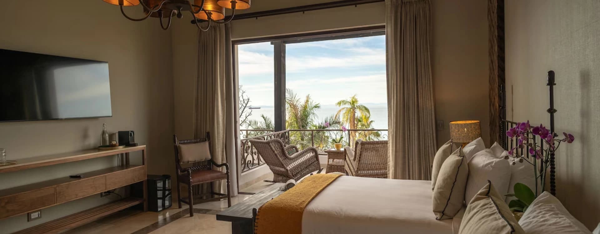 Bed with a mustard runner facing the window with a sea view