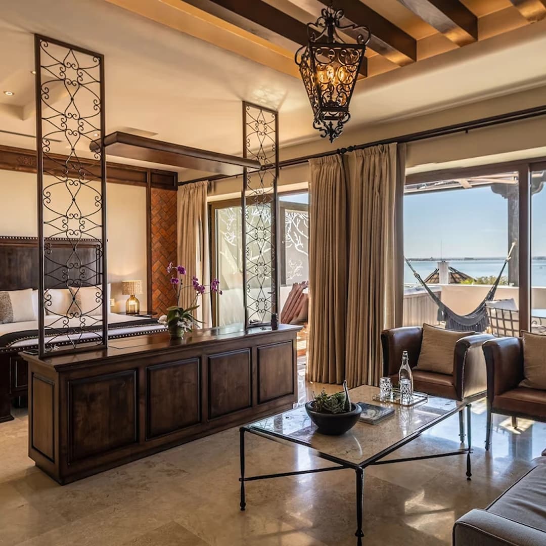 A suite with wooden beams, a wrought-iron screen, leather armchairs and a terrace with a hammock facing the sea