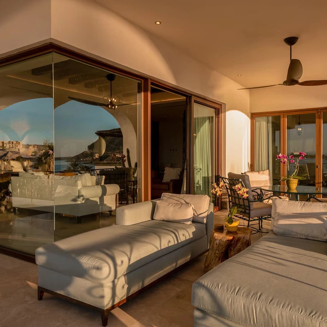An open lounge with white sofas and glass walls onto the terrace and the bay