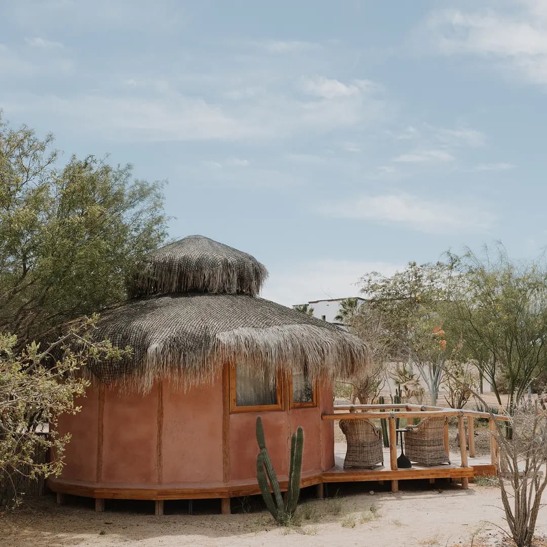 One of the Botanic Bungalows: a round clay cabin with a palapa roof and a wooden deck