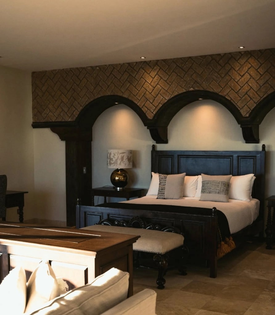Bed with an arched timber headboard under a herringbone brick wall