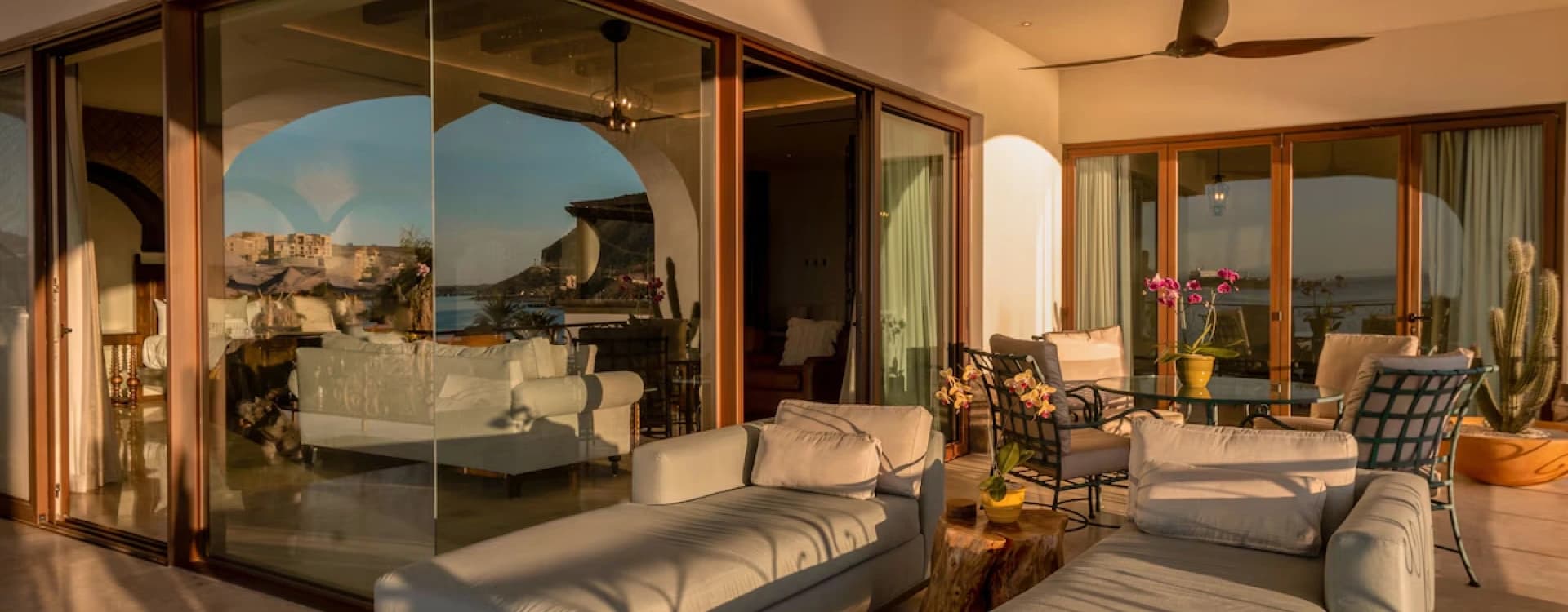 Sala con diván y muros de cristal espejado hacia el mar