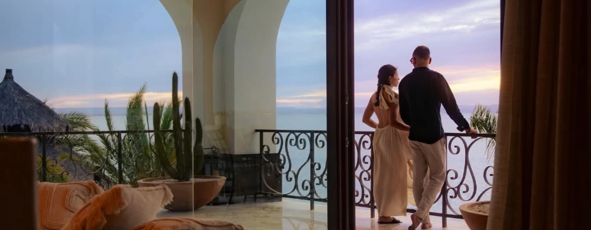 A couple on the terrace, between arches, at sunset over the Gulf of California