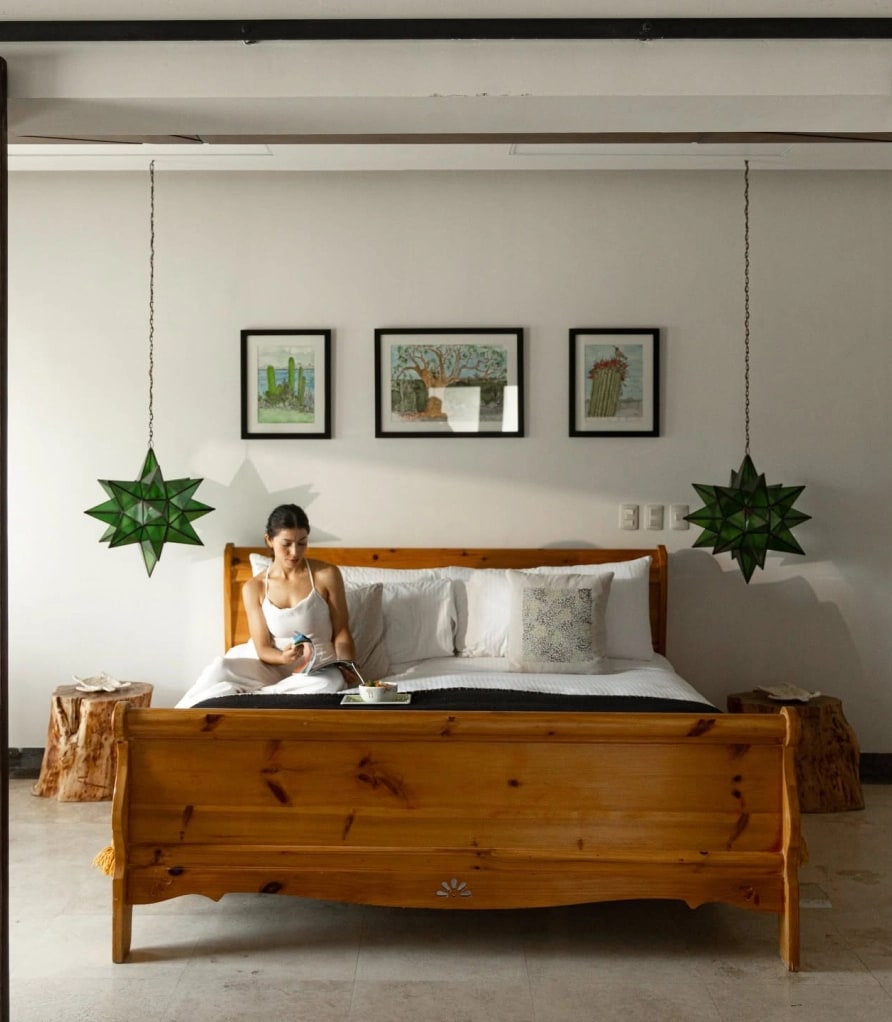Timber sleigh bed with green glass star lanterns and framed prints