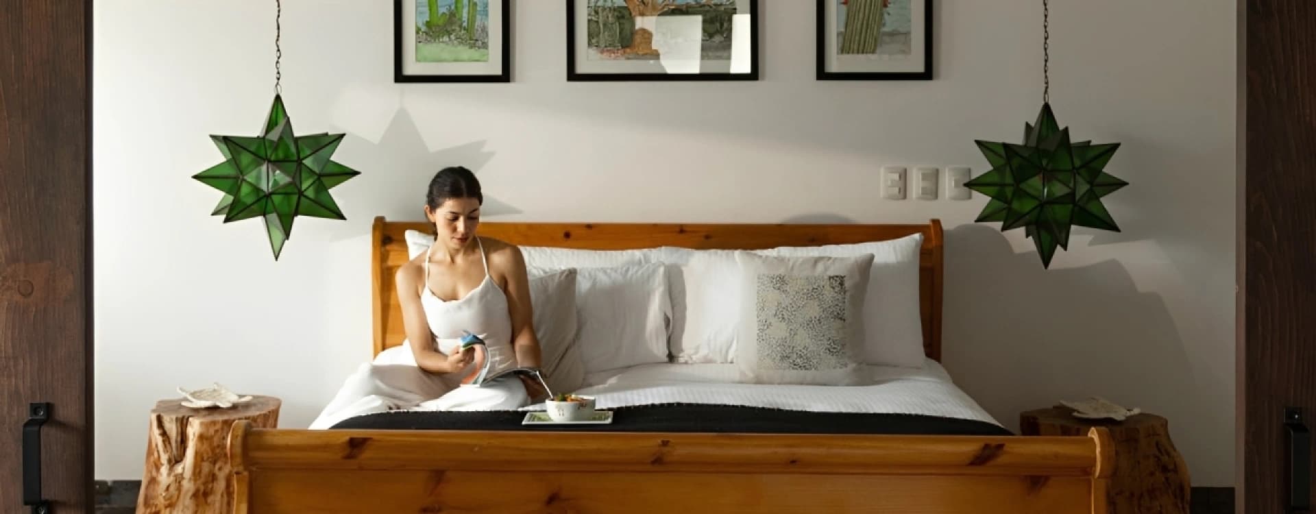 Timber sleigh bed with green glass star lanterns and framed prints