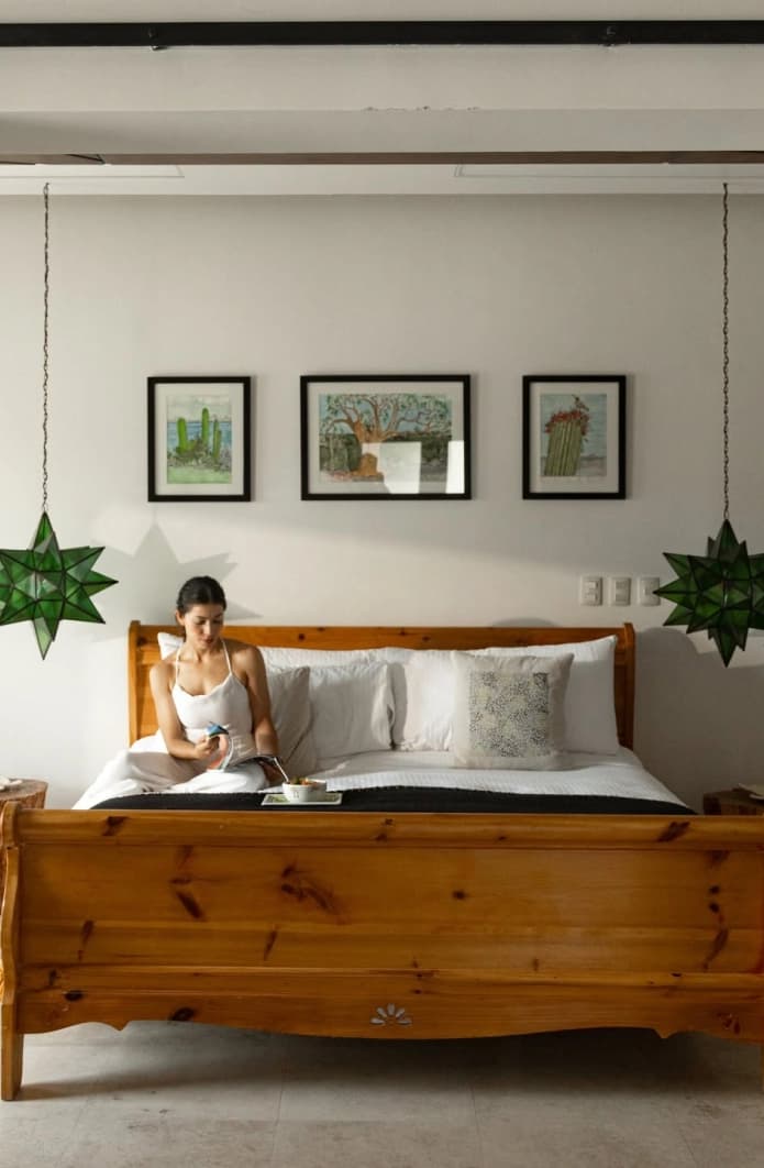 Timber sleigh bed with green glass star lanterns and framed prints