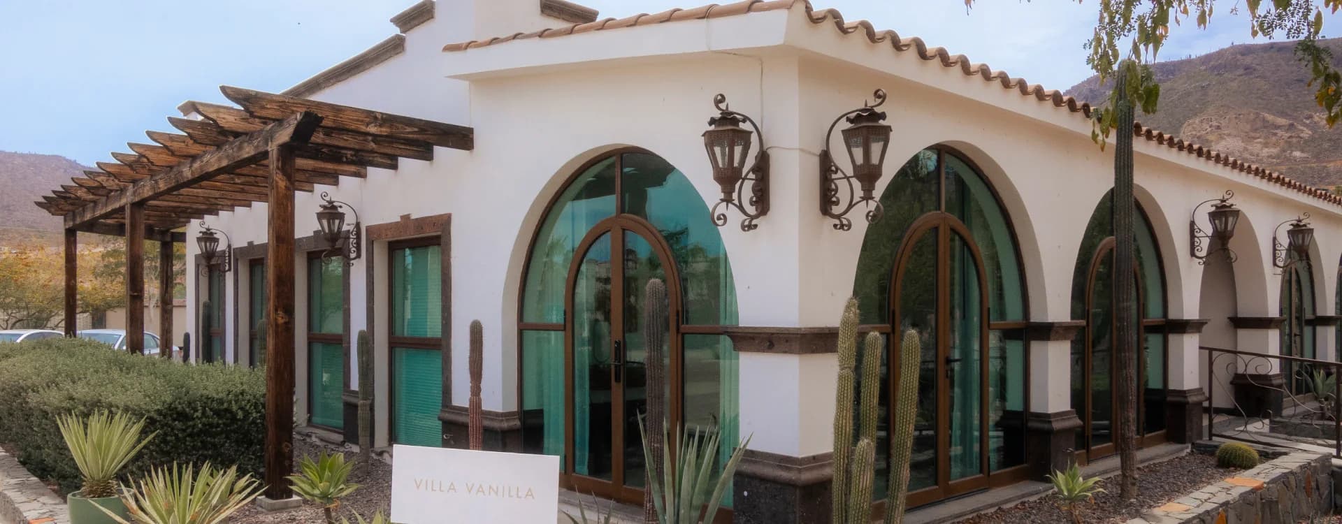 White villa façade with arches and a cactus garden